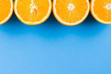 Mavi arka planda sulu turuncu yarısını keser. Turuncu meyve, narenciye minimal kavramı. Yaratıcı yaz yemekleri minimalist arka plan. Üstteki görünüm, kopya alanı