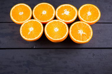 Siyah ahşap tahta üzerinde portakal meyvesi. Siyah arka planda sulu turuncu yarısı. Turuncu meyve, narenciye minimal kavramı. Üstteki görünüm, kopya alanı