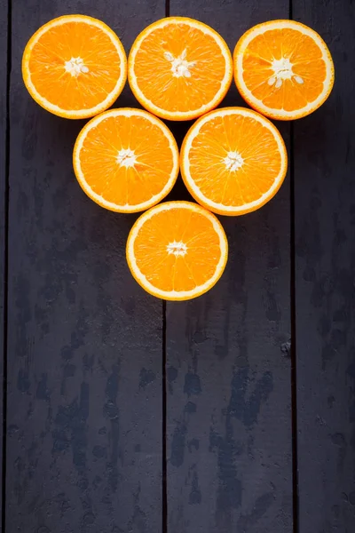 Oranges fruit on black wooden boards. Halves of juicy orange on black background. Orange fruit, citrus minimal concept. Top view, copy space