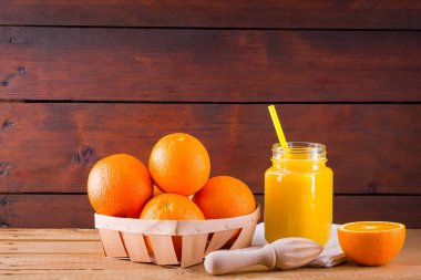 Beyaz peçete üzerinde turuncu meyve ve meyve suyu. Manuel juicer ile meyve suyu yapmak için Narenciye meyve. Ahşap panolardaki ahşap kutuda Portakallar. Portakal suyu ile Mason kavanoz