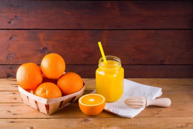 Beyaz peçete üzerinde turuncu meyve ve meyve suyu. Manuel juicer ile meyve suyu yapmak için Narenciye meyve. Ahşap panolardaki ahşap kutuda Portakallar. Portakal suyu ile Mason kavanoz