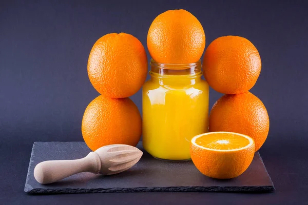 Orange fruits and juice on black background. Citrus fruit for making juice with manual juicer. Oranges on slate board. Mason jar with orange juice. Copy space