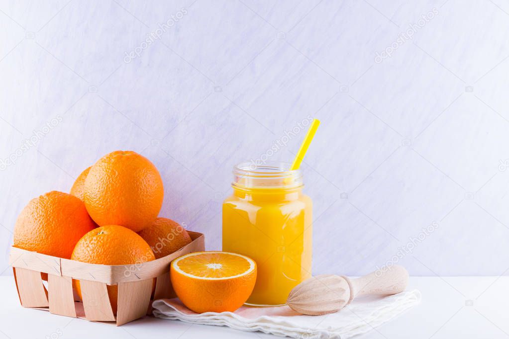 Orange fruits and juice on white background. Citrus fruit for making juice with manual juicer. Oranges in wooden box on white napkin. Mason jar with orange juice