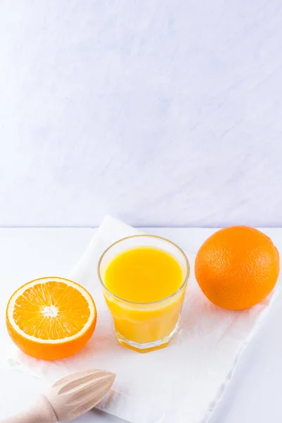 Orange fruits with juice, concept. Orange juice and halves of oranges on white background. Citrus for making juice and manual juicer. Whole and squeezed oranges and glass of juice