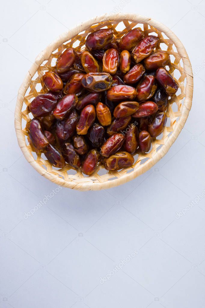 Dried dates on white background. Holy month of Ramadan, concept. Righteous Muslim lifestyle. Starvation. Dates in wooden basket. Vegetarian food. Copy space