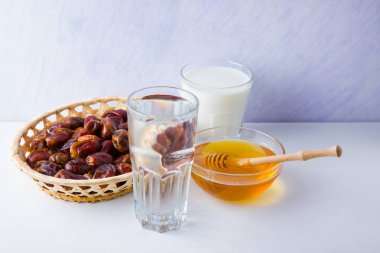 Kurutulmuş hurma, süt ve bal beyaz arka plan üzerinde. Kutsal Ramazan ayı, konsept. Erdemli Müslüman yaşam tarzı. Aç -lık. Ahşap sepet ve bal da tarihler. Vejetaryen yemekleri. Kopyalama alanı