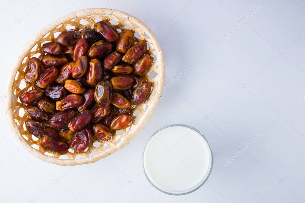 Dried dates and milk on white background. Holy month of Ramadan, concept. Righteous Muslim lifestyle. Starvation. Dates in wooden basket and water. Vegetarian food. Copy space