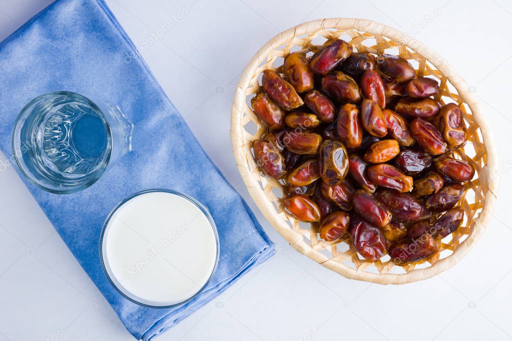 Dried dates and milk on white background. Holy month of Ramadan, concept. Righteous Muslim lifestyle. Starvation. Dates in wooden basket and water. Vegetarian food. Copy space