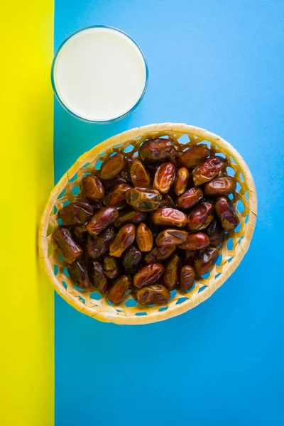 Dried dates and milk on a yellow blue background. Holy month of Ramadan, concept. Righteous Muslim lifestyle. Starvation. Dates in a wooden basket in the style of minimalism