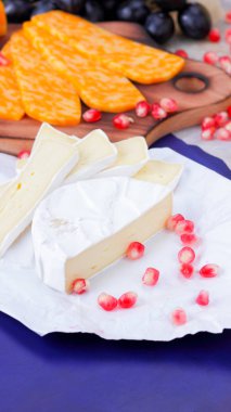Farklı peynir ve meyve türleri. Dilimlenmiş camembert ve nar. Yumuşak ve sert peynir ve fındık. Camembert ve mavi arka plan üzerinde üzüm. Vejetaryen yemekler