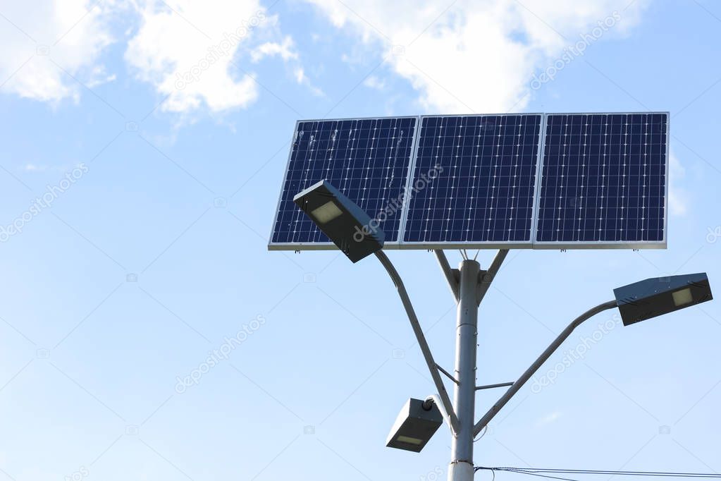 Solar cell lamp on sky background. Light support with lantern and installed solar panels on blue sky. Alternative energy from the sun
