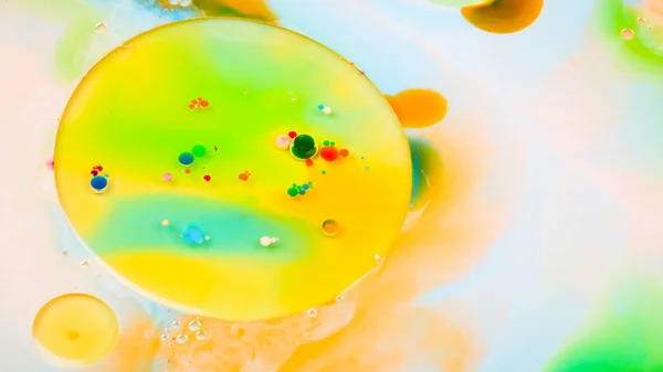 Multicolored background with oil on liquid. Abstract golden green background on liquid. Pattern with multicolored spots. Fluid art