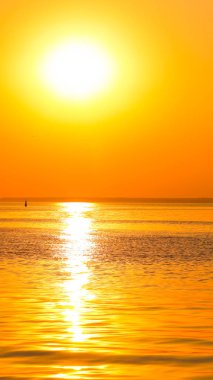 Denizüzerinde turuncu gün batımı. Denizin ufkunda parlak turuncu güneş. Altın renkte minimalizm tarzında gün batımı. Deniz den tatil