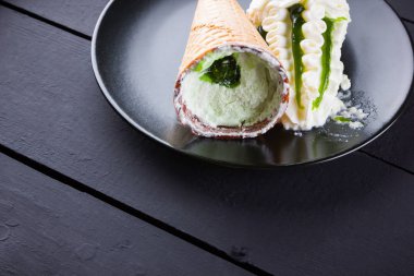 Siyah arka planda dondurma külahı, yaz konsepti. Siyah tabakta reçel ile tatlı. Minimalizm tarzında dondurma ile Waffle konisi. Kopyalama alanı