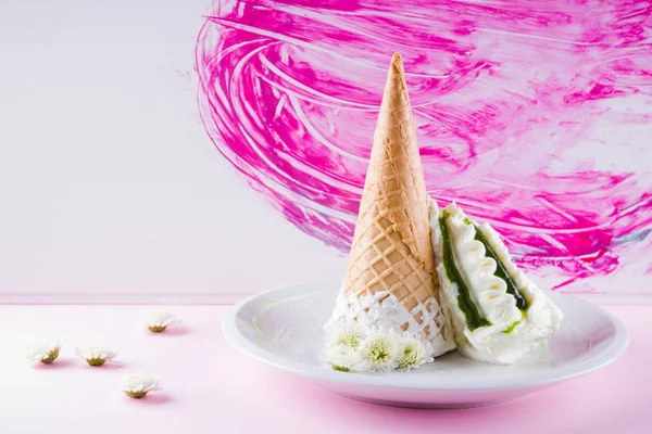 Ice cream cone and white flowers on pink background, summer concept. Dessert with jam on white plate. Waffle cone with ice cream in pastel colors. Copy space