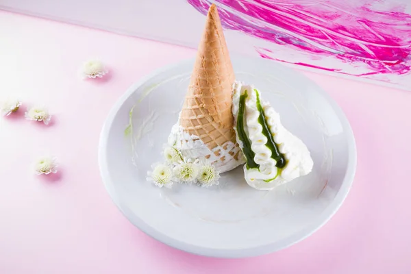 Ice cream cone and white flowers on pink background, summer concept. Dessert with jam on white plate. Waffle cone with ice cream in pastel colors. Copy space