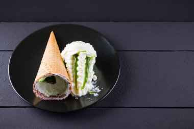 Siyah arka planda dondurma külahı, yaz konsepti. Siyah tabakta reçel ile tatlı. Minimalizm tarzında dondurma ile Waffle konisi. Kopyalama alanı