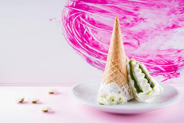 Ice cream cone and white flowers on pink background, summer concept. Dessert with jam on white plate. Waffle cone with ice cream in pastel colors. Copy space