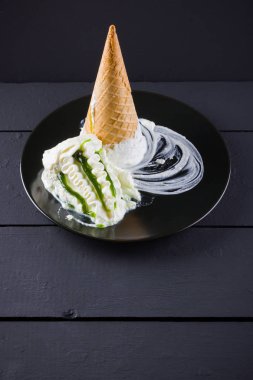 Siyah arka planda dondurma külahı, yaz konsepti. Siyah tabakta reçel ile tatlı. Minimalizm tarzında dondurma ile Waffle konisi. Kopyalama alanı