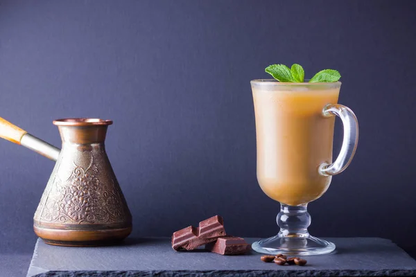 Turkish coffee concept. Copper coffee pot (Cezve) and coffee beans. Latte, chocolate and fresh mint on a slate board. Copy space