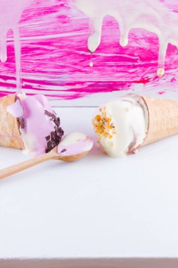 Pembe beyaz bir arka plan üzerinde eritilmiş dondurma. Pop art tarzında iki dondurma külahı. Tahta kaşıkla yaz sütü tatlısı. Yaz konsepti