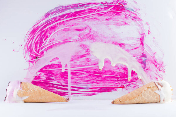 Растаявшее мороженое с шоколадом и орехами на розовом фоне. Два мороженых в стиле поп-арта. Летний молочный десерт в вафельном конусе. Летняя концепция
