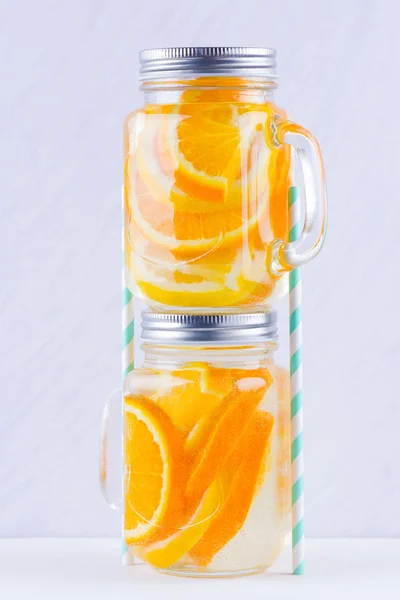 Infused water with fruits on white background. Mug delicious refreshing drink of mix fruits on white background. Iced summer drink in mason jar. Minimalism