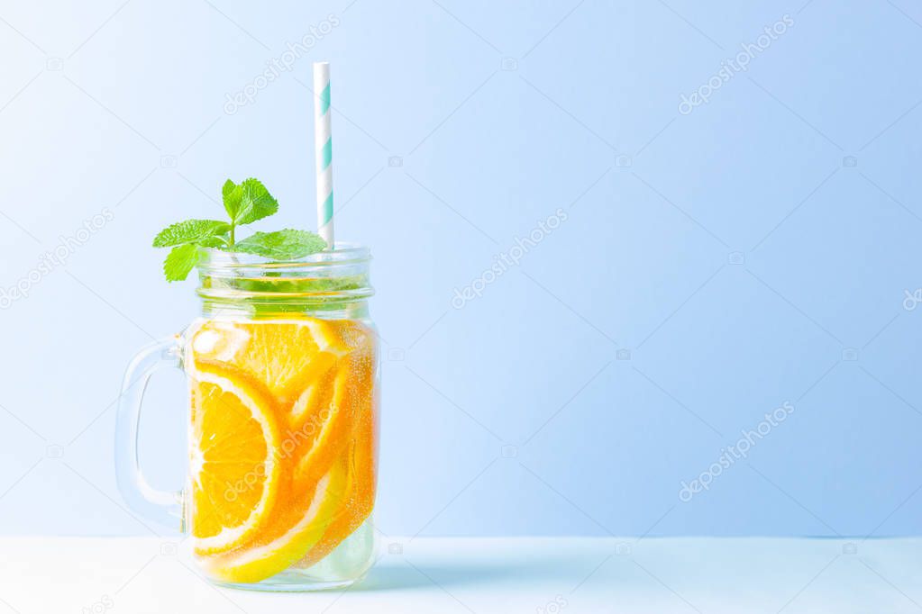 Infused water with fruits on blue background. Mug delicious refreshing drink of mix fruits with mint on blue background. Iced summer drink in mason jar. Minimalism