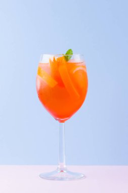 Kokteyl Aperol Spritz mavi pembe arka plan üzerinde. Pop art tarzı İtalyan kokteyl aperol spritz. Pastel arka planda yaz trendy içki