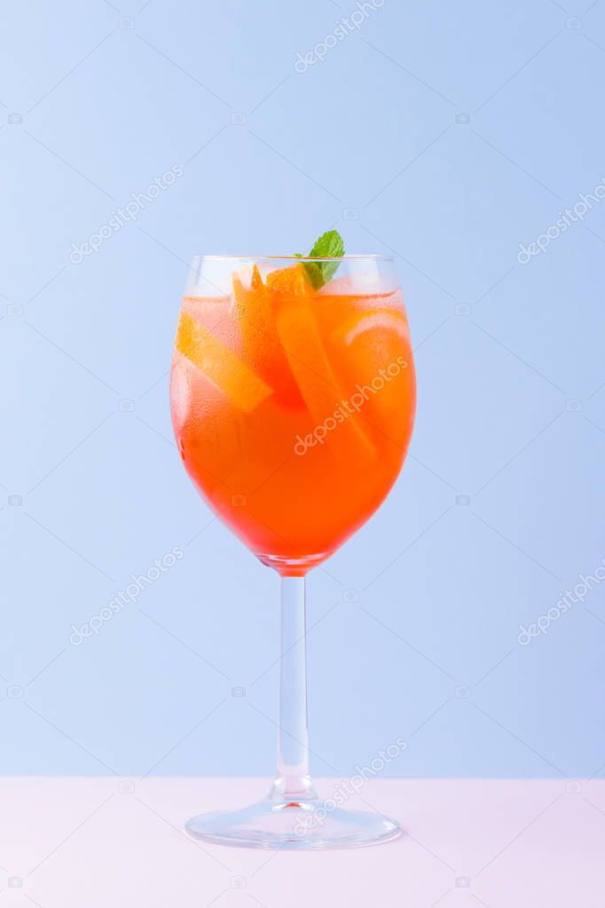 Cocktail Aperol Spritz on a blue pink background. Italian cocktail aperol spritz in pop art style. Summer trendy drink on pastel background