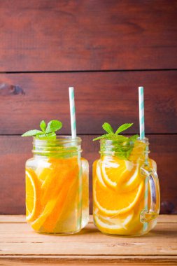 Meyve portakal, limon ve nane ile su aşılanmış. Ahşap tahtalar üzerinde mason kavanozda buzlu yaz içkisi. Taze ev yapımı limonata