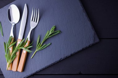 Çatal bıçak, kaşık, kayrak taş üzerinde çatal seti. biberiye ile utlery. Siyah arka plan. Kopya alanı. Üstte görüntü