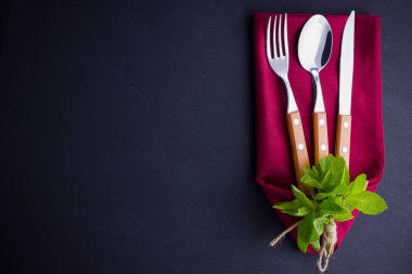 Çatal bıçak takımı. Bıçak, kaşık, tahta taş üzerinde çatal. bordo peçete ve ip ile utlery. Siyah arka planda nane. Masa ayarı. Üstte görüntü