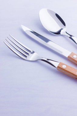 Çatal bıçak seti: bıçak, çatal, beyaz arka plan üzerinde kaşık. Masa ayarı. Ahşap saplı çatal bıçak takımı konsepti - lakonik minimalist tasarım. Üstte görüntü