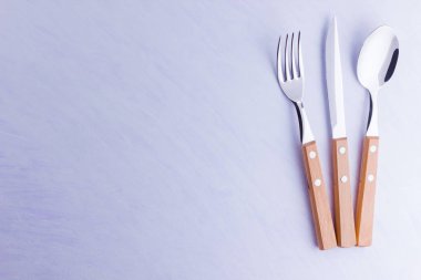 Çatal bıçak seti: bıçak, çatal, beyaz arka plan üzerinde kaşık. Masa ayarı. Ahşap saplı çatal bıçak takımı konsepti - lakonik minimalist tasarım. Üstte görüntü