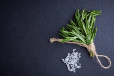 Biberiye demeti siyah bir arka plan üzerinde ip ile bağlı. Taze biberiye ve arduvaz taşında tuz. Kopya alanı ile et yemekleri pişirmek için otlar. Üstte görüntü