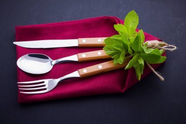 Çatal bıçak takımı. Bıçak, kaşık, tahta taş üzerinde çatal. bordo peçete ve ip ile utlery. Siyah arka planda nane. Masa ayarı. Üstte görüntü