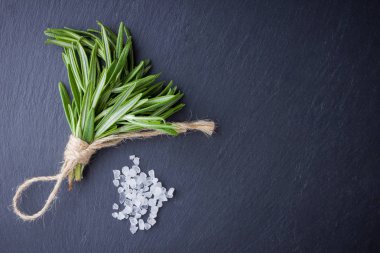 Biberiye demeti siyah bir arka plan üzerinde ip ile bağlı. Taze biberiye ve arduvaz taşında tuz. Kopya alanı ile et yemekleri pişirmek için otlar. Üstte görüntü