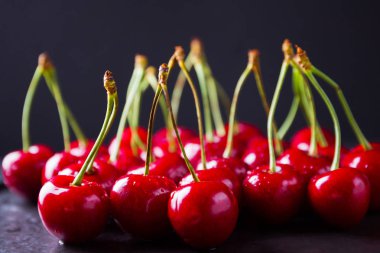 Siyah bir arka plan üzerinde kırmızı kiraz. Karanlık bir arka plan üzerinde su damlatatlı kiraz. Vegan için kırmızı meyveler. Üstte görüntü