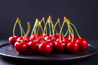 Siyah bir arka plan üzerinde kırmızı kiraz. Karanlık bir arka plan üzerinde su damlatatlı kiraz. Vegan için kırmızı meyveler. Üstte görüntü