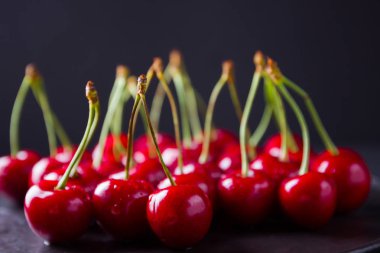 Siyah bir arka plan üzerinde kırmızı kiraz. Karanlık bir arka plan üzerinde su damlatatlı kiraz. Vegan için kırmızı meyveler. Üstte görüntü