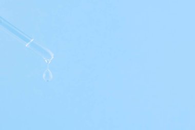 Kozmetik işlemler için serum. Mavi arka planda serum. Bir damla ile kozmetik pipet. Minimalizm. Yakın çekim