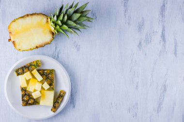 Gri bir arka plan üzerinde ananas dilimleri. Beyaz bir tabakta dilimlenmiş ananas. Vegan için tropikal meyve. Üst te. Kopyalama alanı