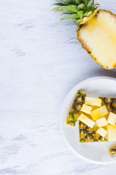 Pineapple slices on a gray background. Sliced pineapple on a white plate. Tropical fruit for vegan. Top view. Copy space