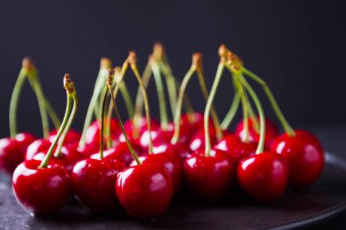 Siyah bir arka plan üzerinde kırmızı kiraz. Karanlık bir arka plan üzerinde su damlatatlı kiraz. Vegan için kırmızı meyveler. Üstte görüntü