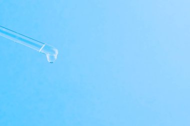 Kozmetik işlemler için serum. Mavi arka planda serum. Bir damla ile kozmetik pipet. Minimalizm. Yakın çekim