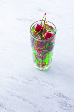 Vişne kokteyli. Beyaz arka plan üzerinde bir bardak kırmızı kiraz. Tatlı kiraz ile yeşil gazlı içecek. Kopyalama alanı