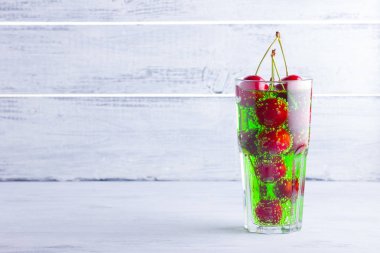 Vişne kokteyli. Beyaz arka plan üzerinde bir bardak kırmızı kiraz. Tatlı kiraz ile yeşil gazlı içecek. Kopyalama alanı