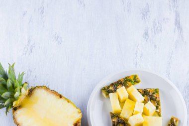 Gri bir arka plan üzerinde ananas dilimleri. Beyaz bir tabakta dilimlenmiş ananas. Vegan için tropikal meyve. Üst te. Kopyalama alanı