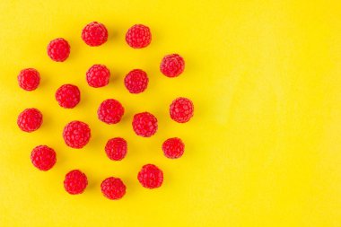 Sarı arka planda ahududu deseni. Renkli diyet ve sağlıklı gıda kavramı. Ahududu arka plan. Üst te. Düz yatıyordu. Kopyalama alanı